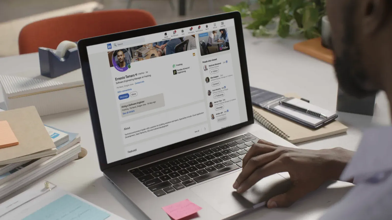 Someone at a desk viewing a LinkedIn profile that is advertising a job
